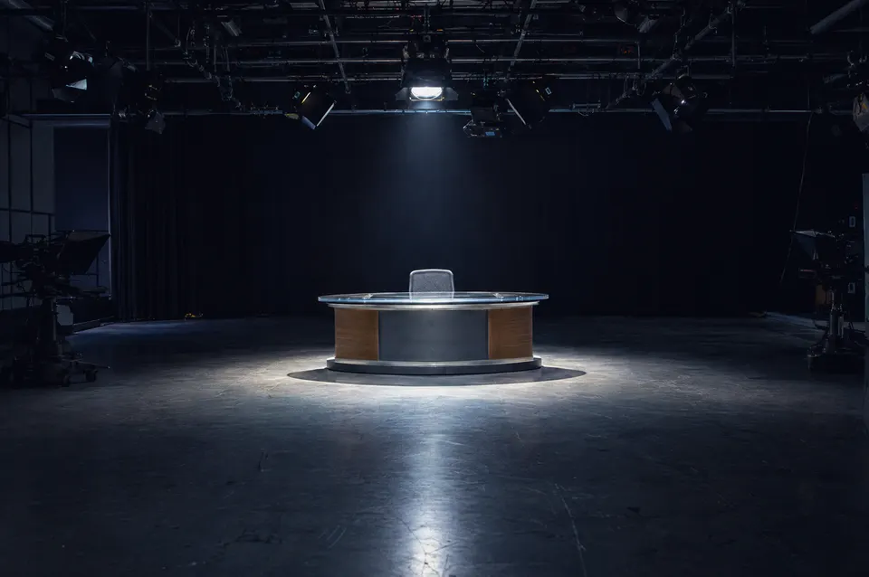 Illustration: An empty broadcast studio under a spotlight